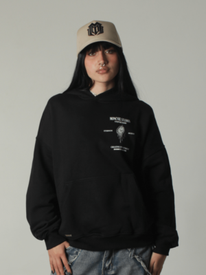 Modelo vistiendo gorra Monogram Beige con logo bordado oscuro, combinada con hoodie negro oversize de Moncyre Studios, estilo streetwear premium minimalista.